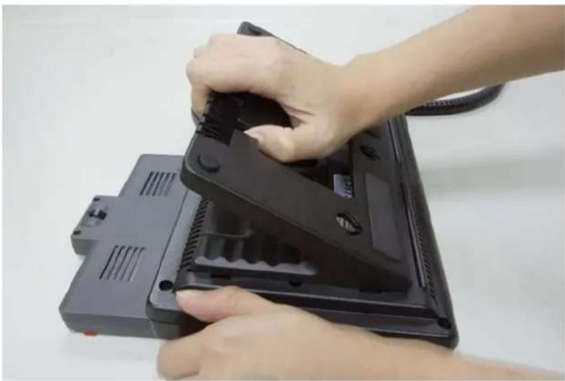 Close-up of hands installing or adjusting a black electronic device component (no visible text or symbols)