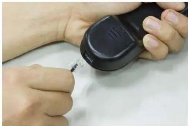 Close-up of hands using a handheld device to apply a small object (no visible text or symbols)