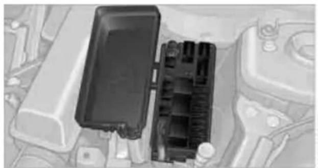 Close-up of a car engine bay with a black plastic enclosure and battery (no visible text or symbols)