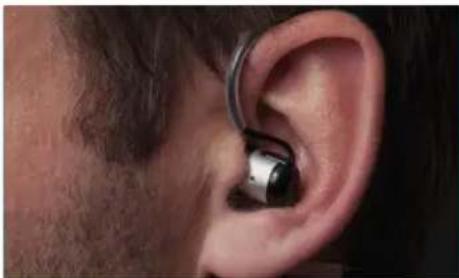 Close-up of a person's ear with an earpiece, showing metallic components (no text or symbols visible)