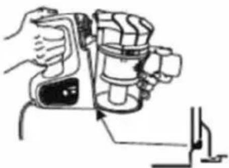 Line drawing of a hand operating a portable device with a handle and control panel (no text or symbols)