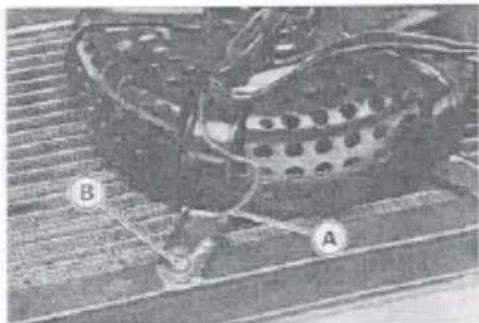 Close-up of a perforated mechanical component with labeled points A and B, placed on a textured surface (no readable text or symbols)