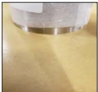 Close-up of a metallic cylindrical object on a yellow surface, no visible text or symbols