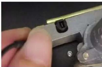 Close-up of a hand using a metal tool to adjust or install a mechanical component (no visible text or symbols)