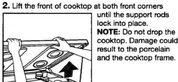 2. Lift the front of cooktop at both front corners until the support rods lock into place. NOTE: Do not drop the cooktop. Damage could result to the porcelain and the cooktop frame.