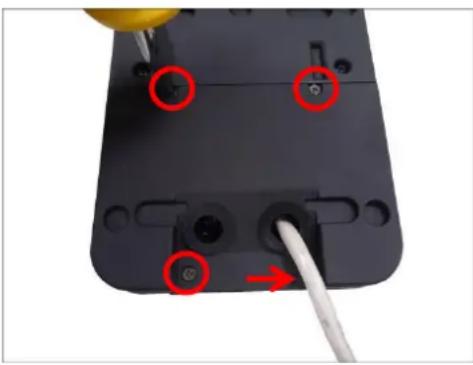 Close-up of a black electronic device with four circular ports and a white cable inserted, no visible text or symbols