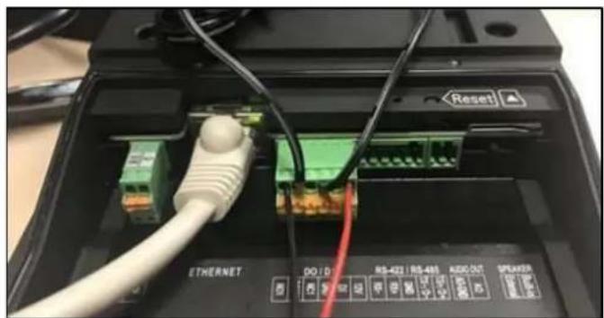 Close-up of an Ethernet device showing internal components including a green connector, white cable, and red indicator lights (no readable text or symbols)