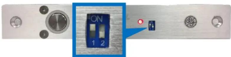 Close-up of a metallic electronic device with a blue ON/OFF switch and two circular indicators (no readable text or symbols)