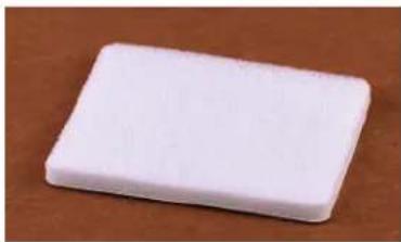 White rectangular object on a brown surface, resembling a button or eraser (no text or symbols visible)