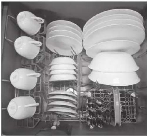 Interior view of a kitchen with multiple white ceramic dishes arranged in tiered trays and a rack of cutlery (no text or symbols visible)