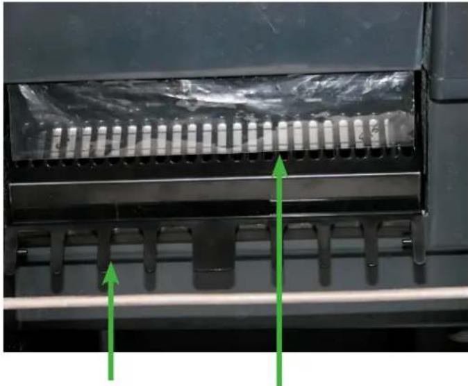 Close-up of a mechanical component with metallic grating and green directional arrows indicating motion or force (no text or symbols)