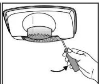 Hand holding a screwdriver to cut a circular object on a surface, with no visible text or symbols