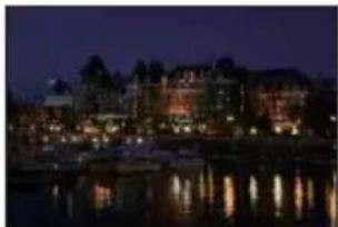 Nighttime cityscape with illuminated buildings reflected in calm water (no visible text or signage)