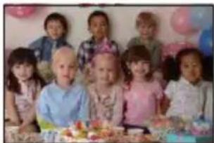 Group photo of children gathered around a table with food and balloons (no visible text or symbols)