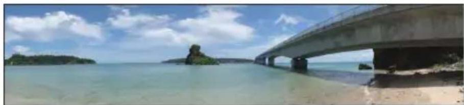 Scenic view of a coastal bridge spanning over turquoise water with small islands and blue sky (no text or symbols visible)