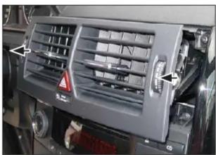 Close-up of a car air vent with airflow indicators and a warning symbol (no readable text or labels)