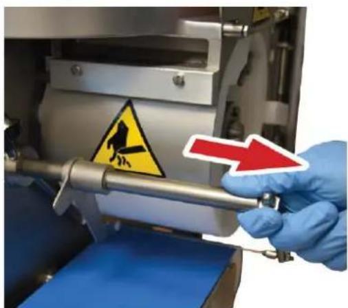 Close-up of a gloved hand holding a mechanical device with warning sign and red arrow, indicating a hazard or hazard warning.