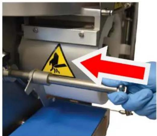 Close-up of a hand holding a metal rod with warning sign and red arrow, indicating hazard or hazard warning.
