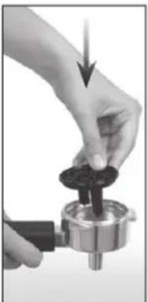 Close-up of a hand using a mechanical tool to press a dark circular component (no text or symbols visible)