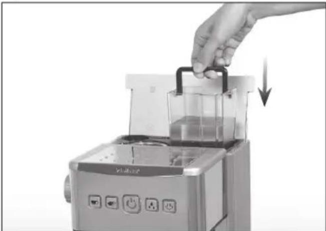 Hand placing a small container into a kitchen appliance with a handle, showing a downward arrow (no text or symbols visible)