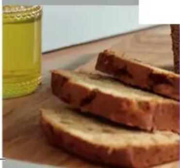 Close-up of sliced bread on a wooden cutting board with a glass of yellow liquid in the background (no text or symbols visible)
