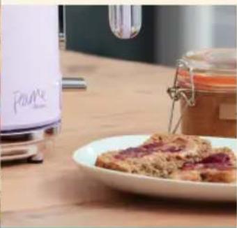 Close-up of a kitchen microwave with a white grater and a glass jar on a wooden table (no visible text or symbols)