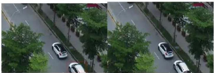 Aerial view of a multi-lane road with several cars parked on the sidewalk, surrounded by trees and parked cars (no visible text or signage)
