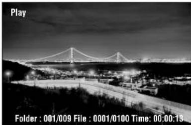 Nighttime black-and-white photo of a suspension bridge over a river with distant buildings and hills (no visible text or symbols)