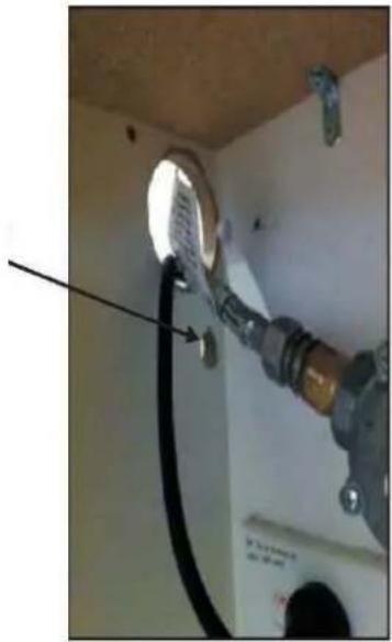 Interior view of a room with a pipe fitting and a circular vent, showing wiring connections (no text or symbols visible)