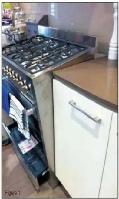 Interior view of a kitchen with an open electric stove and a white cabinet (no visible text or symbols)