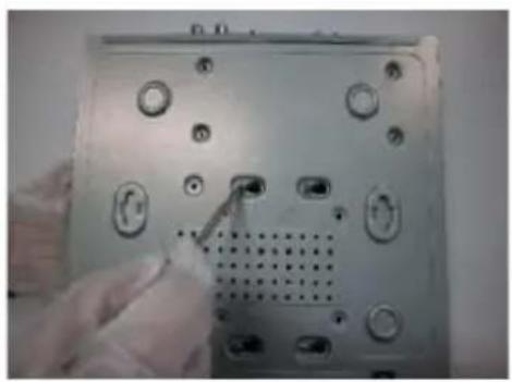 Close-up of a computer monitor rear panel showing ports and buttons, with a hand adjusting the button (no visible text or symbols)