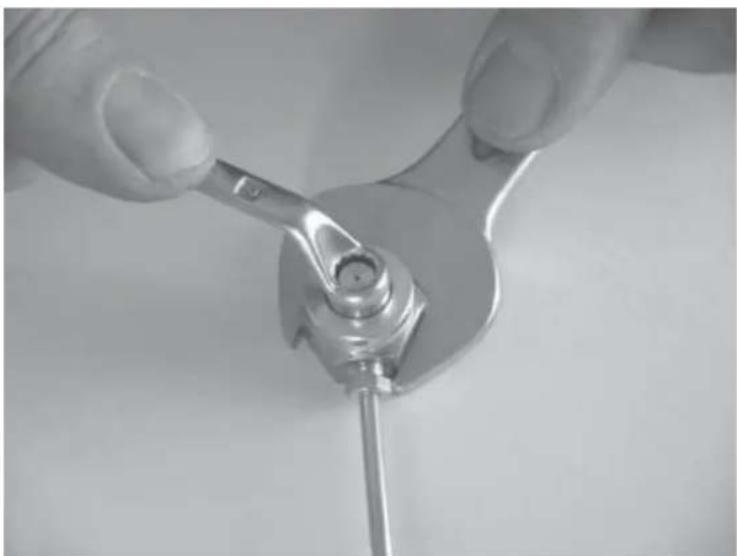 Close-up of hands using a wrench to adjust a mechanical component (no text or symbols visible)