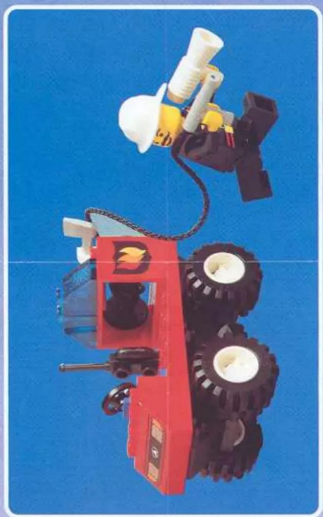 Top-down view of a red and black toy vehicle with white helmet and wheels against a blue background (no text or symbols visible)