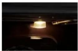 Close-up of a dark vehicle's side mirror with a glowing cylindrical component (no visible text or symbols)