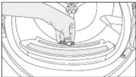 Line drawing of a hand pressing down on a mechanical component (no text or symbols)