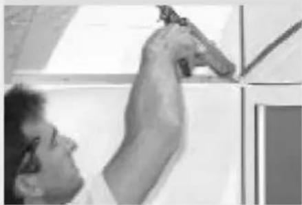 Person holding a small object against a wall, no visible text or symbols