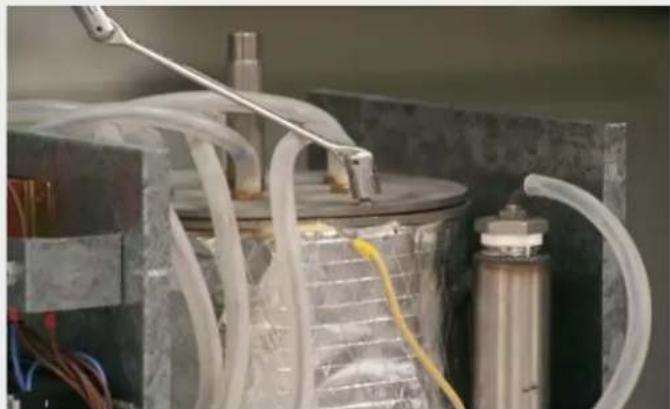 Close-up of a laboratory apparatus with tubing and a metallic container (no visible text or symbols)