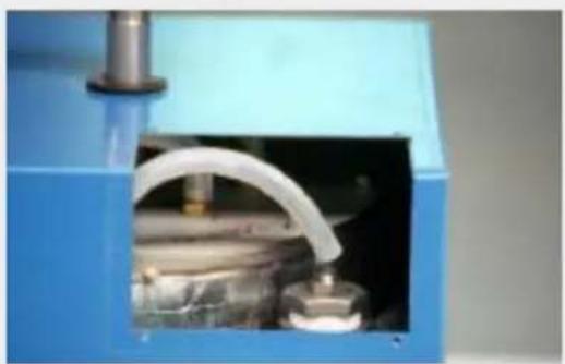 Close-up of a blue industrial machine with a white curved pipe opening, showing internal components (no visible text or symbols)
