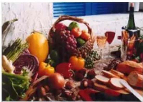 Assorted fresh fruits and vegetables arranged on a table, including lettuce, grapes, and bread slices (no visible text or labels)