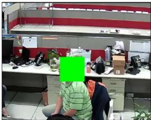 Office interior with two people seated at workstations, surrounded by office supplies and shelves (no visible text or symbols)