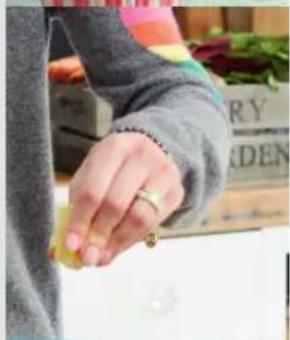 Close-up of a hand holding a small object, wearing a gray sleeve with a decorative ring (no visible text or symbols)