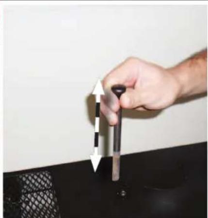 Hand holding a pen with directional arrows pointing to a black object on a dark surface (no text or symbols visible)