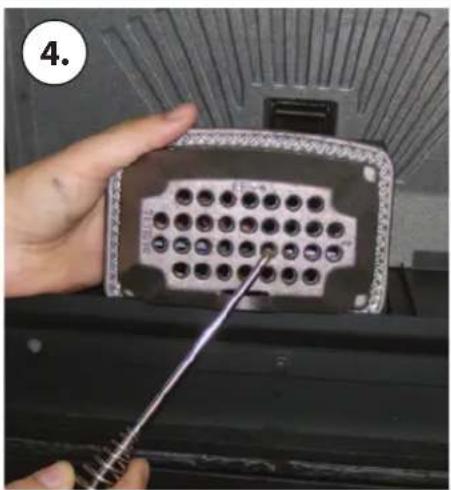 Close-up of a hand holding a connector panel with pins, being adjusted by a tool (no visible text or symbols)