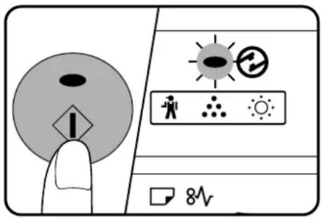 Diagram showing a hand pressing a warning symbol on a device screen with icons for sun, person, radiation, and 8V power.