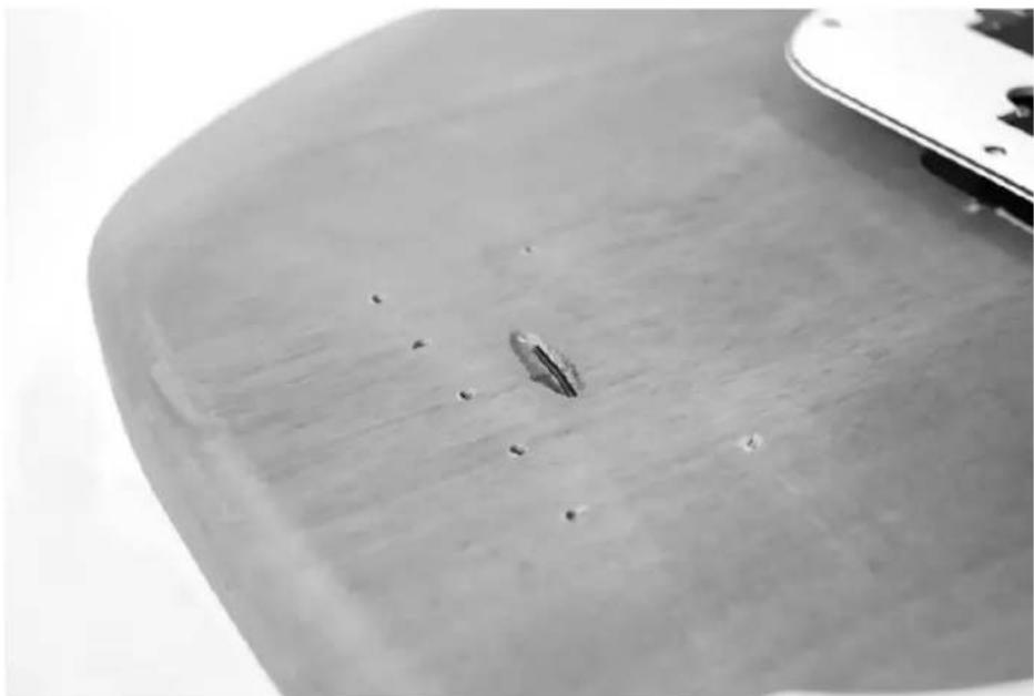 Close-up of a smooth, curved surface with small dark spots and a small central feature, possibly a tool or component (no text or symbols visible)