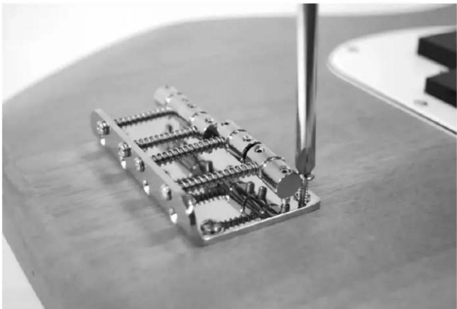 Close-up of a mechanical assembly with a metal bracket and screwdriver inserted, no visible text or symbols