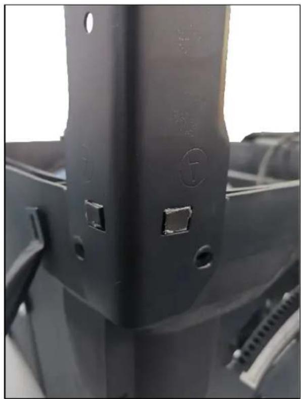 Close-up of a black metal bracket with two small square cutouts and mounting holes (no text or symbols visible)