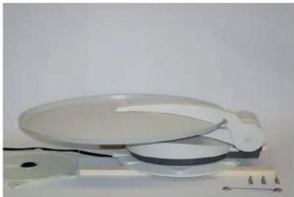 Close-up of a flat plate with a small white object attached, placed on a metal stand (no visible text or symbols)