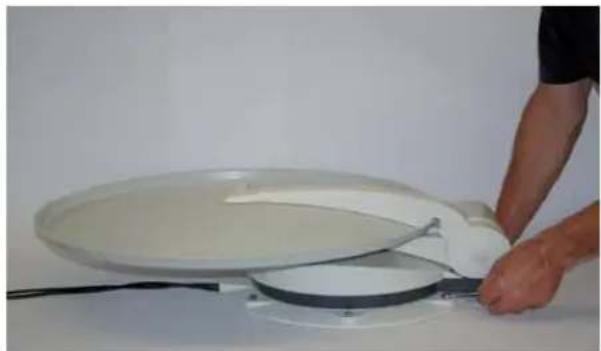 Person using a tool to clean or operate a large white plate on a power stove (no visible text or symbols)