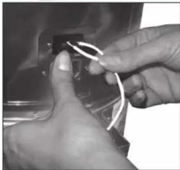 Close-up of hands connecting white wires to a black rectangular component (no text or symbols visible)